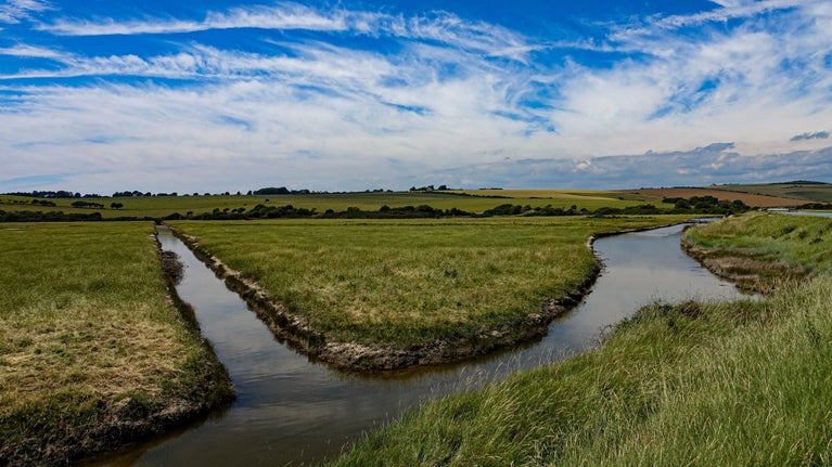 A view across the flat valley fields and meandering river at Cuckmere Valley